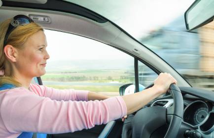 attractive adult woman safe and carefully driving car on suburban road